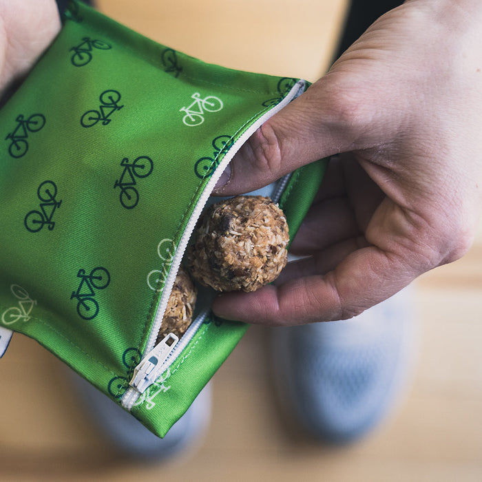 Main qui sort une boule d'énergie d'un mini sac à collation en tissu vert à motif de vélos